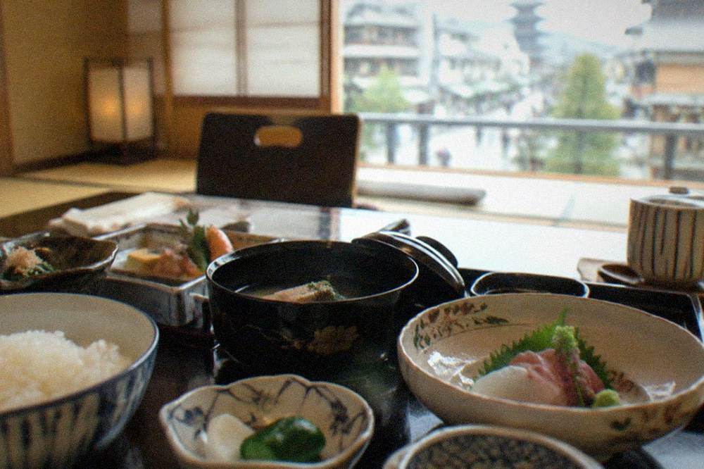A formal kaiseki course laid out in small lacquer and ceramic dishes on a tatami room table