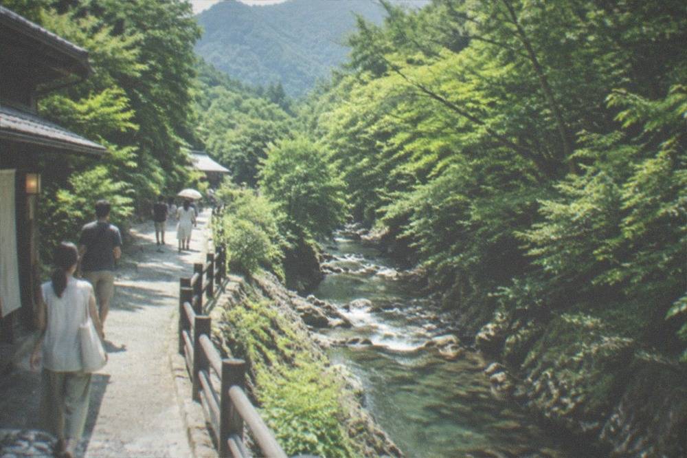 A forested mountain valley trail near Kyoto with a clear stream running beside the path