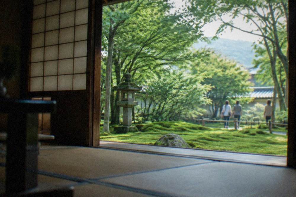 A tatami room in a Kyoto temple with paper screens and a view of a green moss garden
