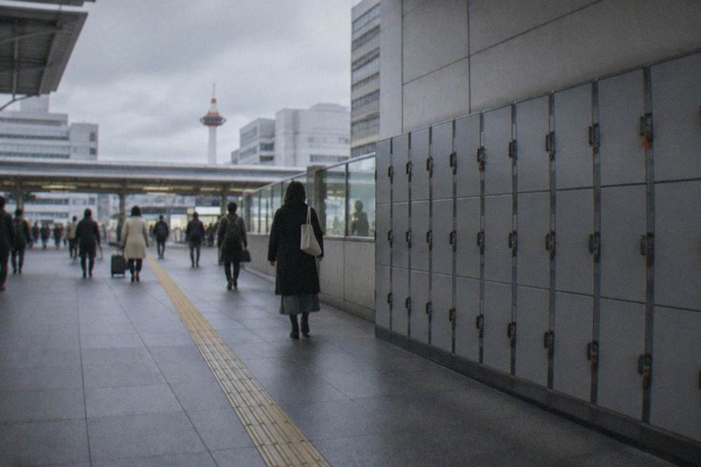 Rows of grey coin lockers along a wall in a Japanese train station concourse