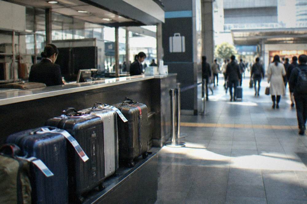 A staffed luggage service counter with tagged suitcases in a Japanese station