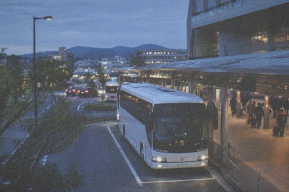A white airport limousine bus parked at a bay outside a station terminal