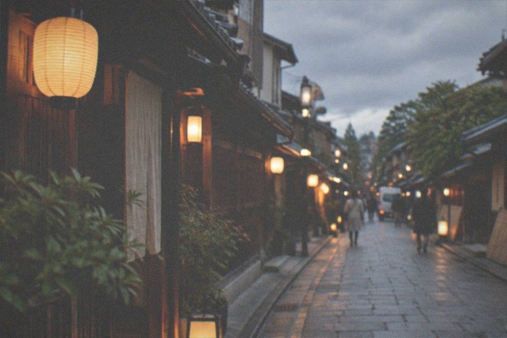 A lantern-lit evening lane in a preserved Kyoto district with wooden facades on both sides