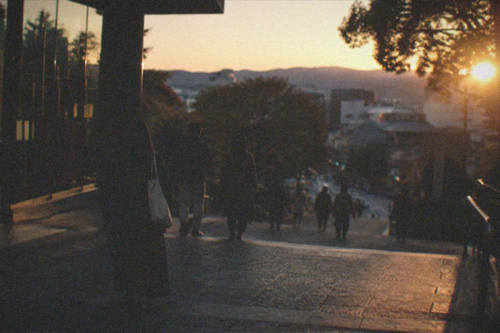 Visitors leaving a museum building at dusk with city lights beyond