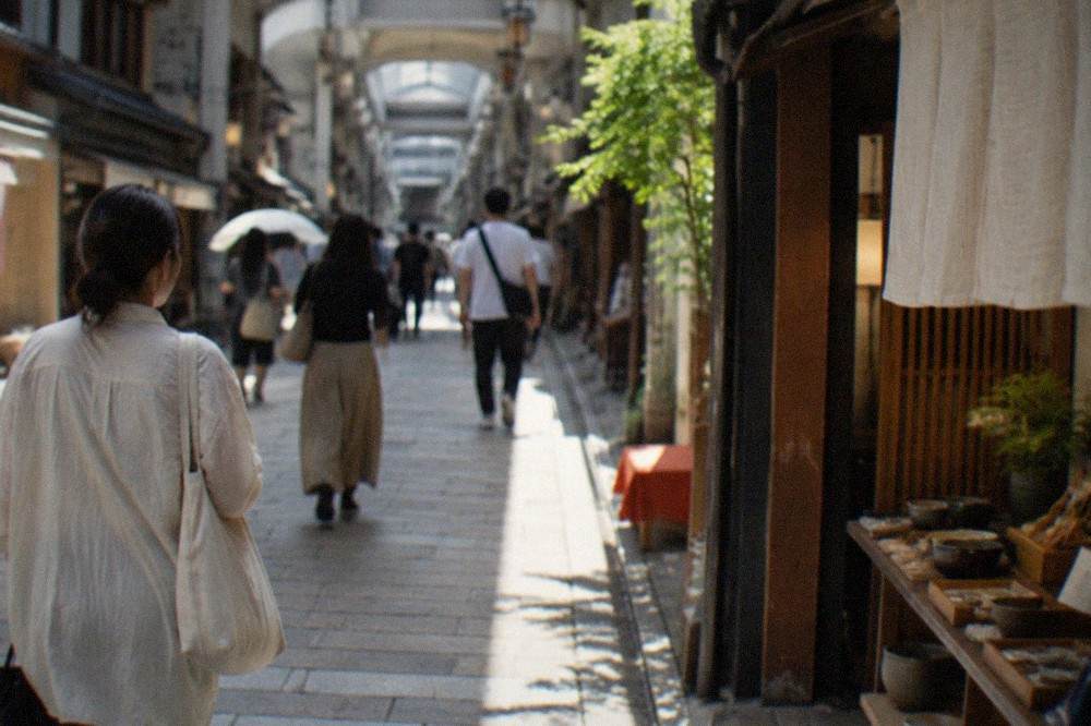 Shoppers on a covered arcade street in downtown Kyoto with shopfronts on both sides