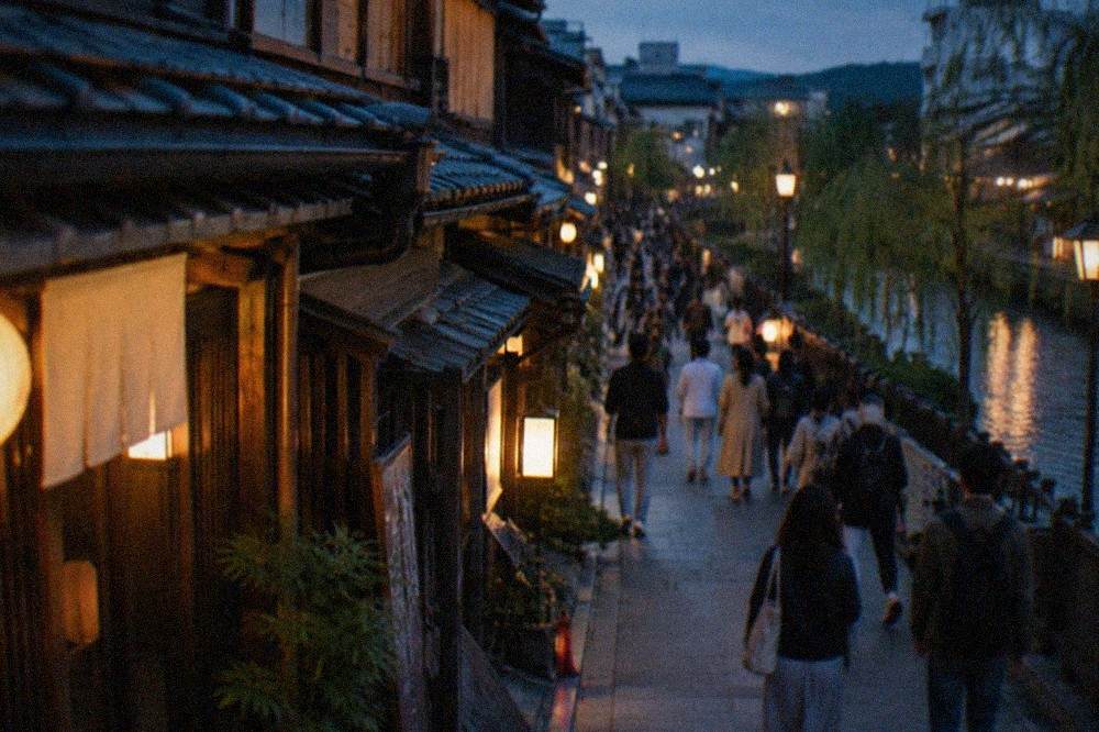 Crowds of people walking along Kiyamachi street in Kyoto with illuminated bar signs in the evening