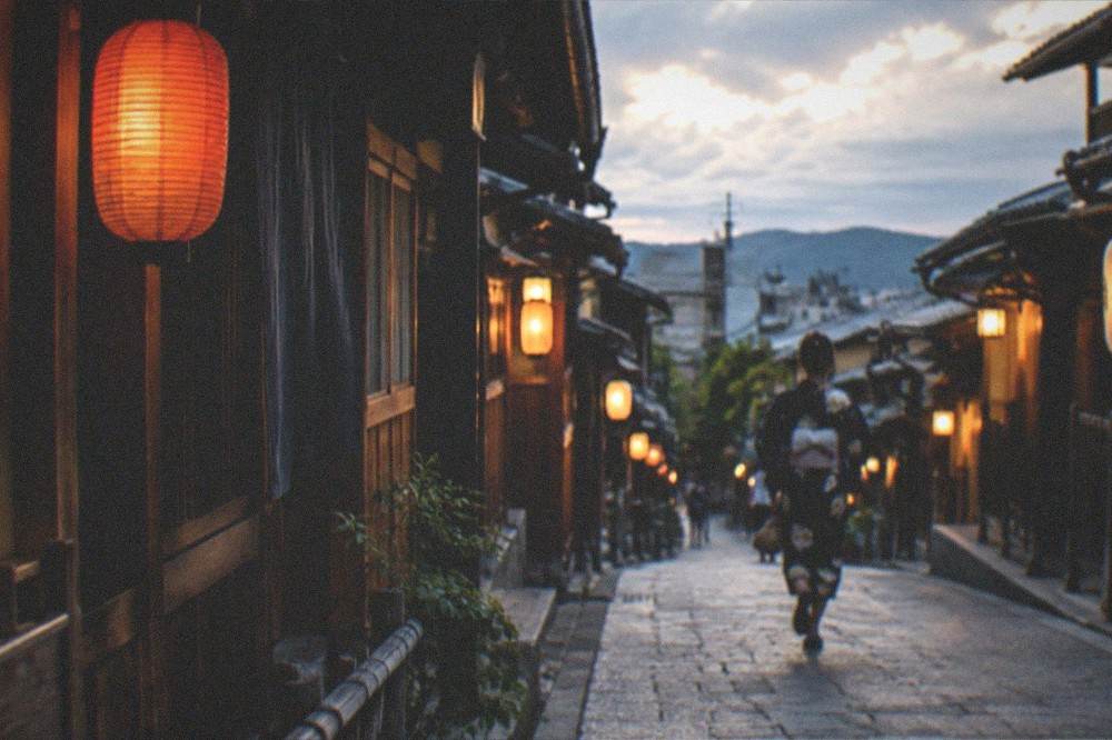 Lanterns and traditional wooden facades along a narrow street in Gion at dusk