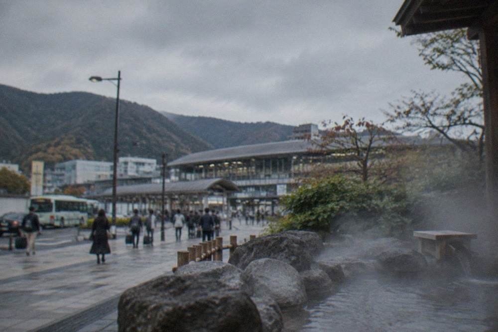 Steam rising from an outdoor stone bath surrounded by forested mountains in rural Kyoto