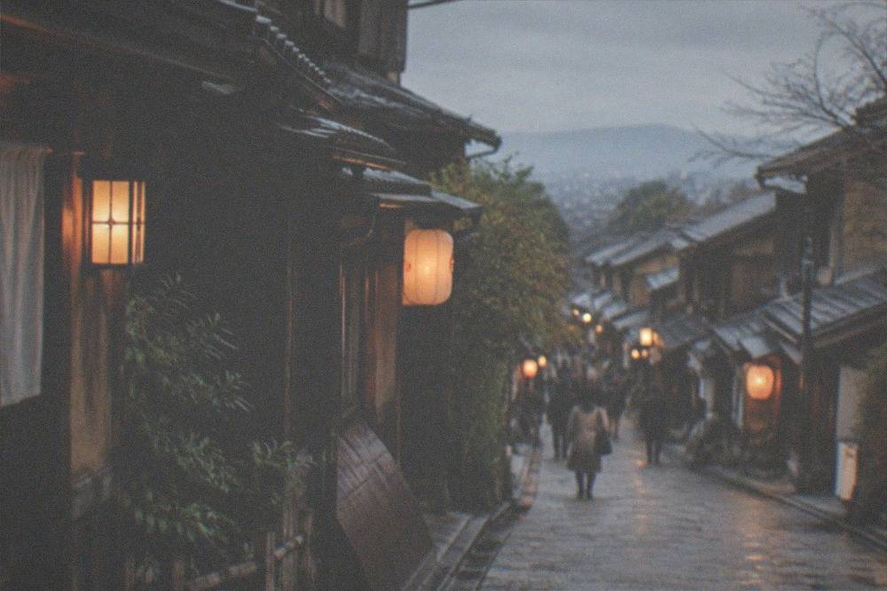 A stone-paved lane in Gion with traditional wooden machiya facades and hanging lanterns in the evening