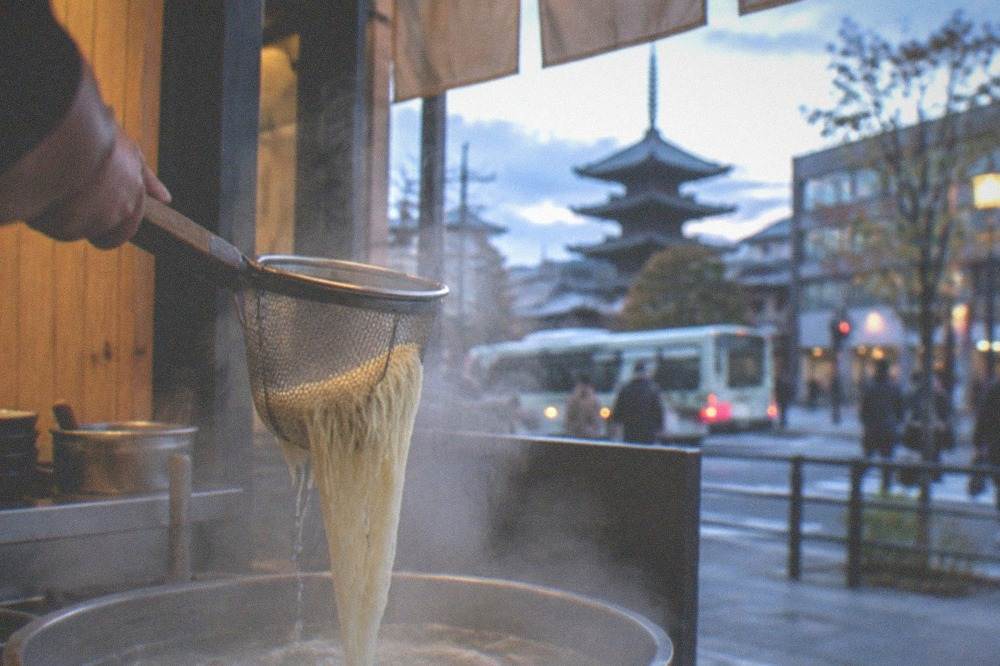 Thin ramen noodles being lifted from boiling water in a strainer