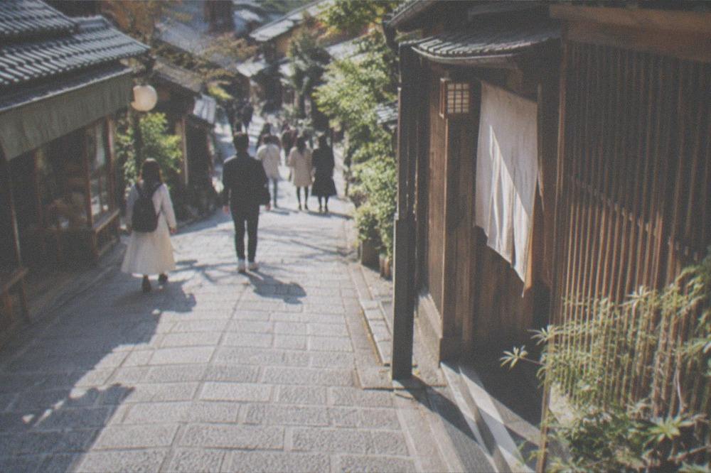 A traditional wooden shopping street in Kyoto with lattice-front shops and stone paving