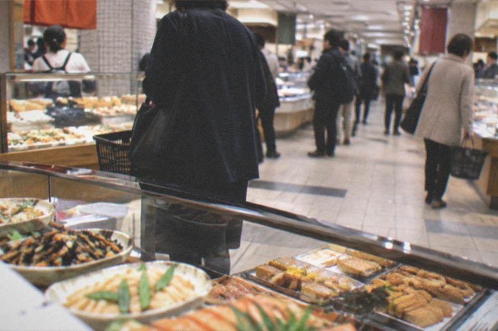 A food basement in a Kyoto department store with glass counters of prepared dishes and shoppers with baskets