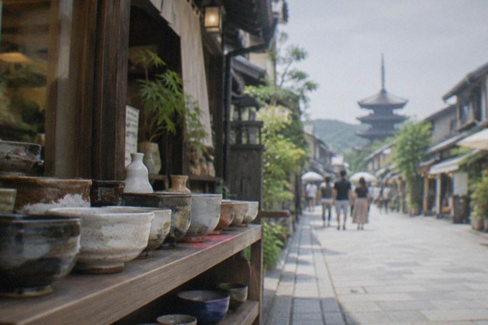 Ceramic tea bowls and pottery arranged on a wooden shelf in a Kyoto shop
