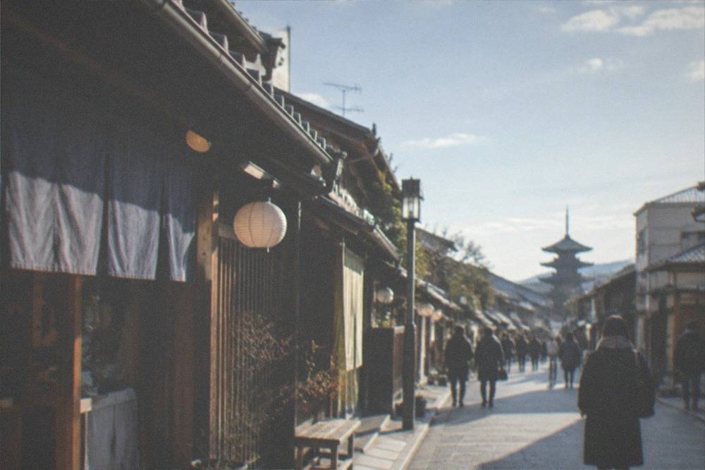A narrow shopping street with traditional wooden storefronts and hanging noren curtains