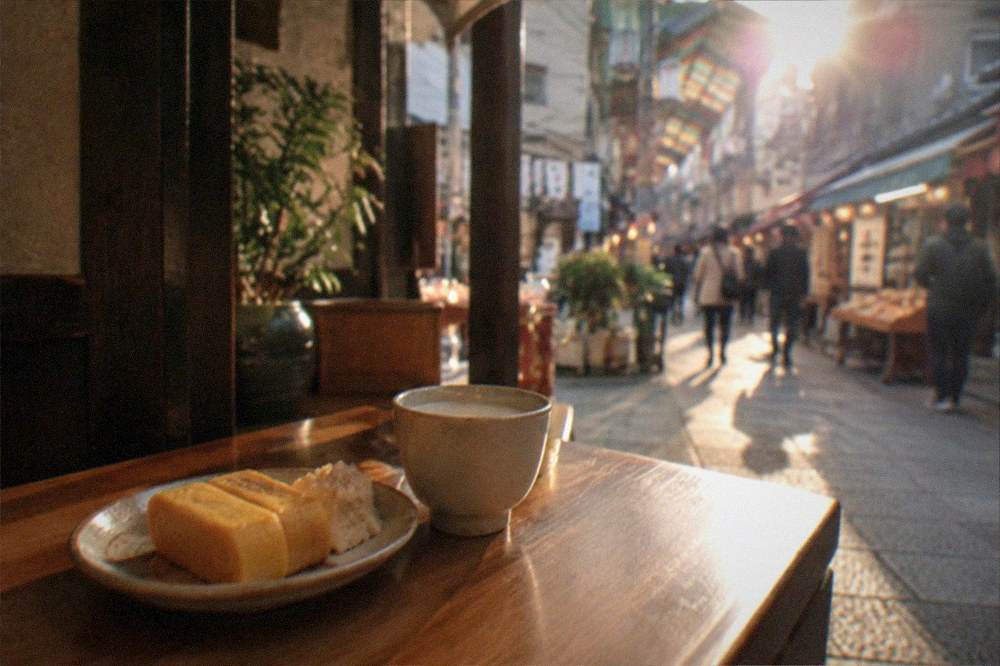 A small plate of rolled omelette and soy milk snacks on a wooden counter