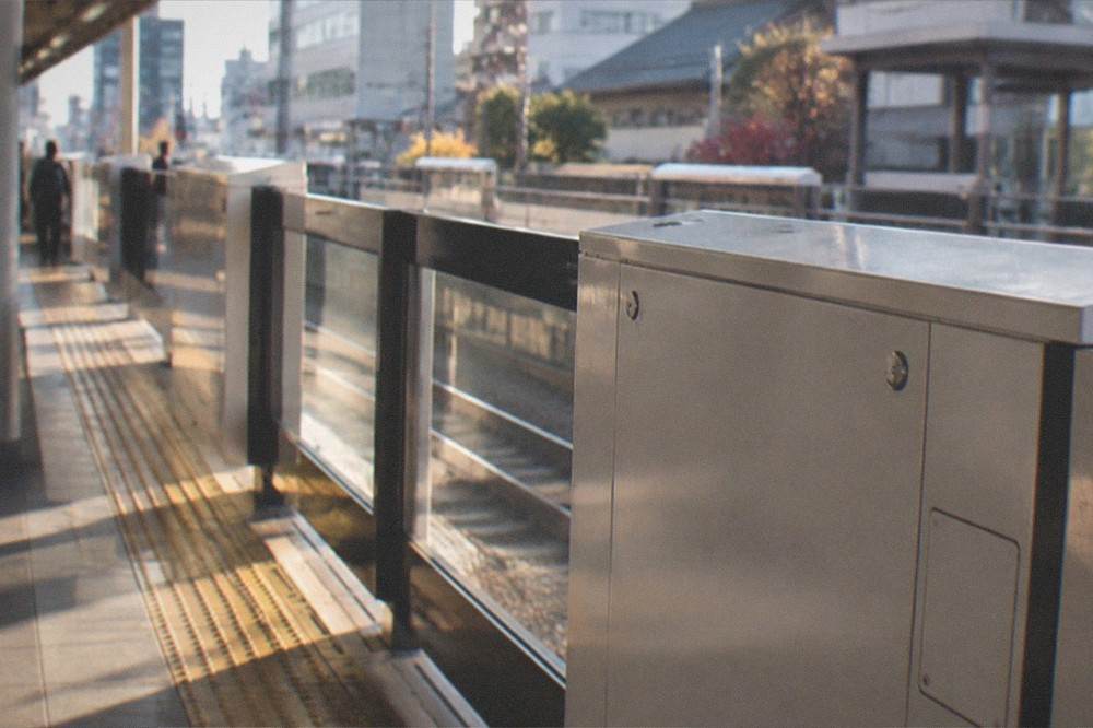 A Kyoto subway platform screen door with a station number sign and an English route map