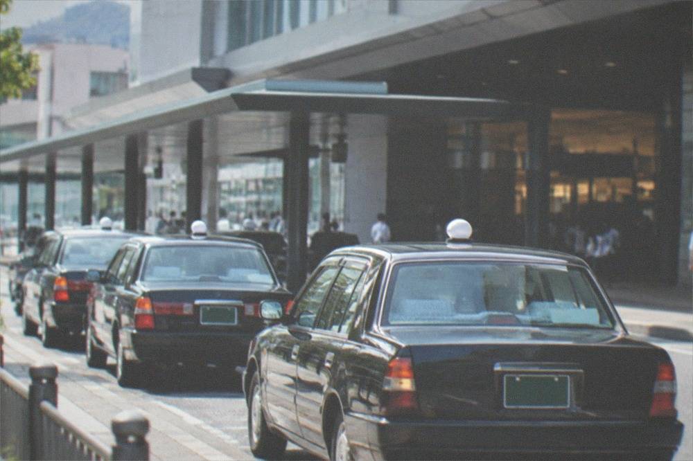 A row of taxis lined up at a dedicated taxi stand outside a Kyoto railway station entrance