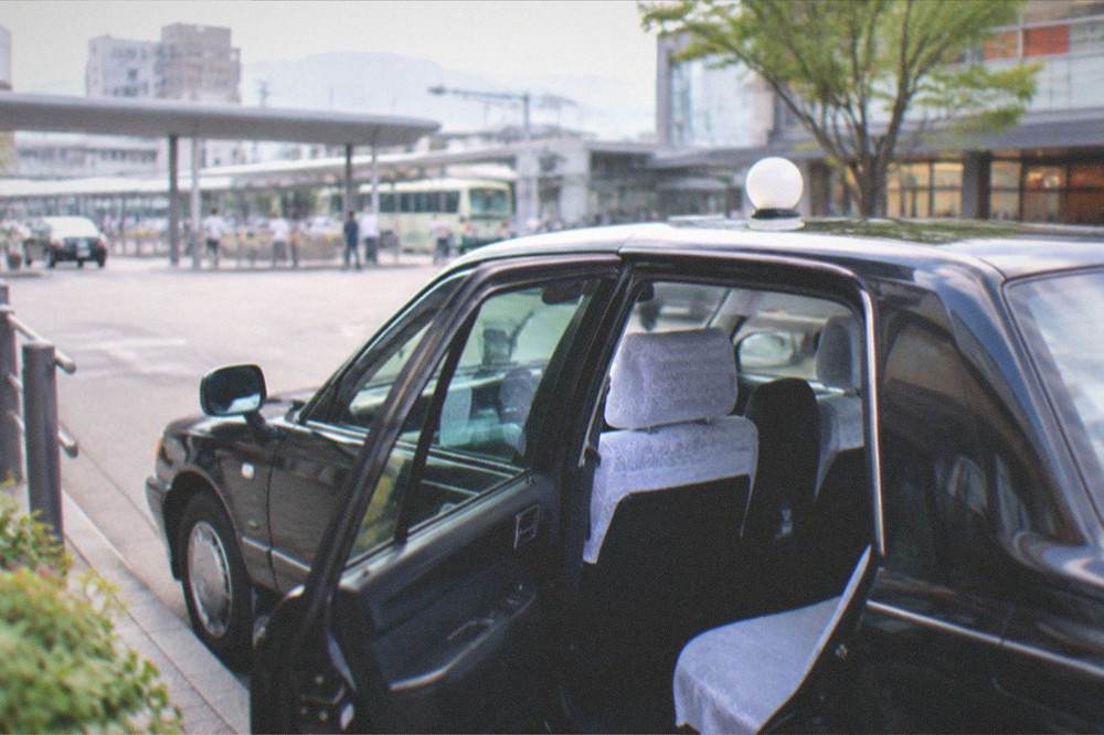 A clean Kyoto taxi interior with white seat covers seen through an open rear door