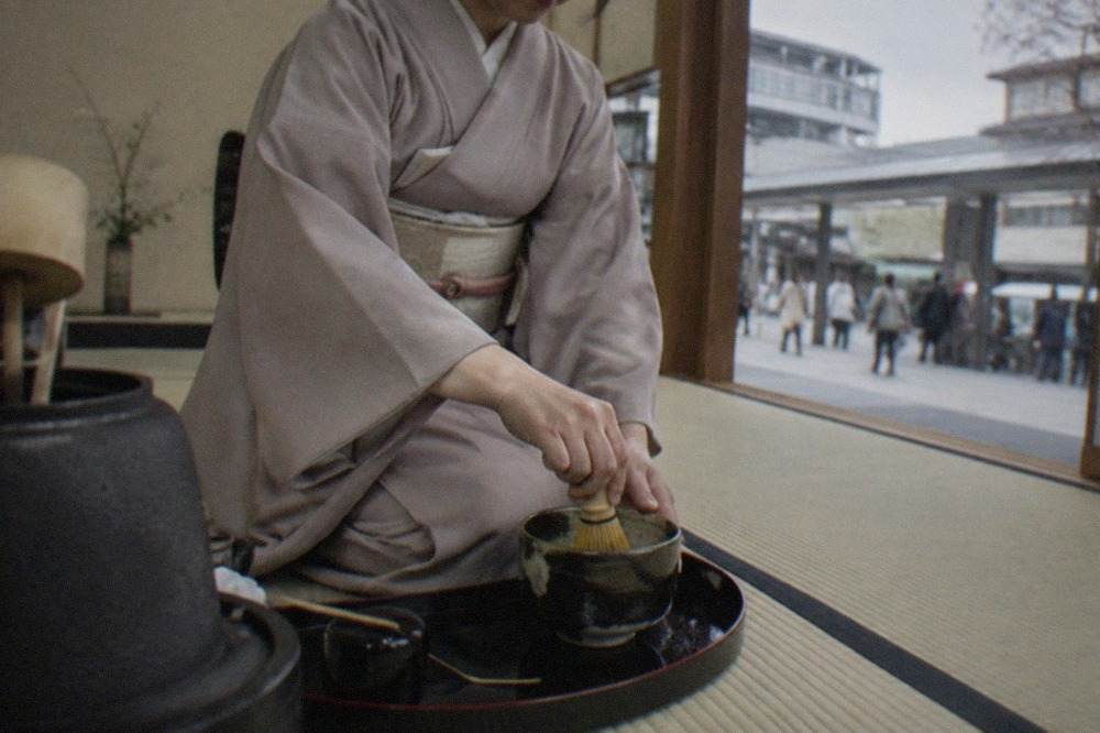 A tea host whisking matcha in a tatami room in Kyoto