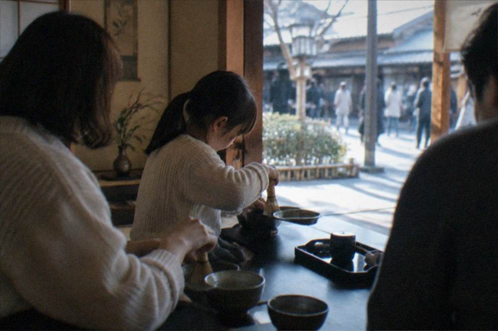 A family learning to whisk matcha together in a Kyoto tea room