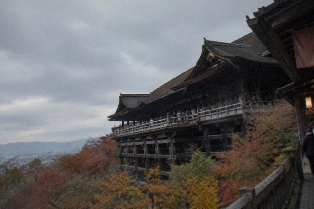 Wooden stage of Kiyomizu-dera extending over a hillside with city rooftops in the distance