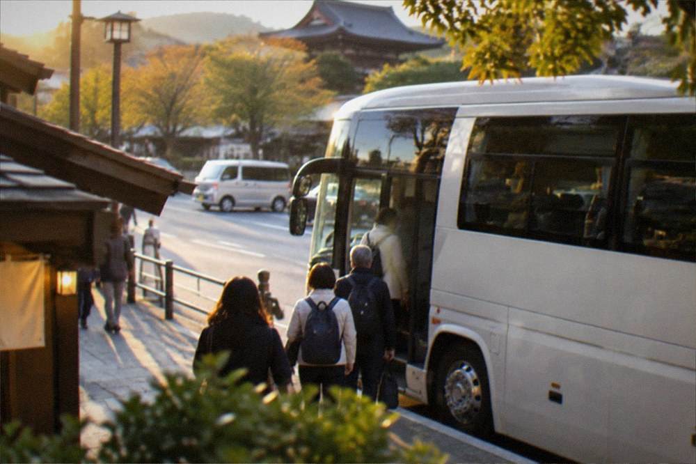 A tour bus parked near Nara Park with passengers boarding in the afternoon