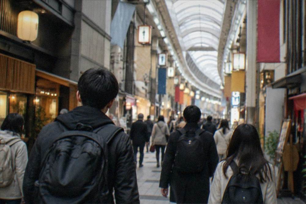 Travellers with backpacks walking through a bright covered shopping arcade in Osaka