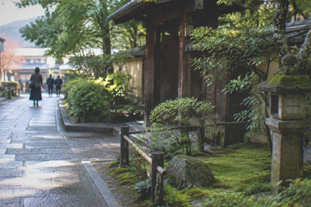 A quiet stone path through a moss-covered Kyoto temple garden in soft morning light