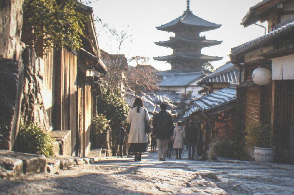Visitors walking the stone steps of Ninenzaka slope toward a pagoda