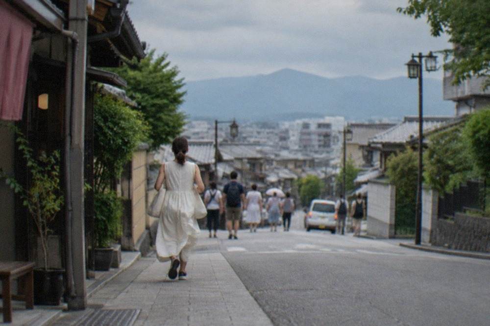 Kyoto rooftops under a wide summer sky with the surrounding mountains on the horizon