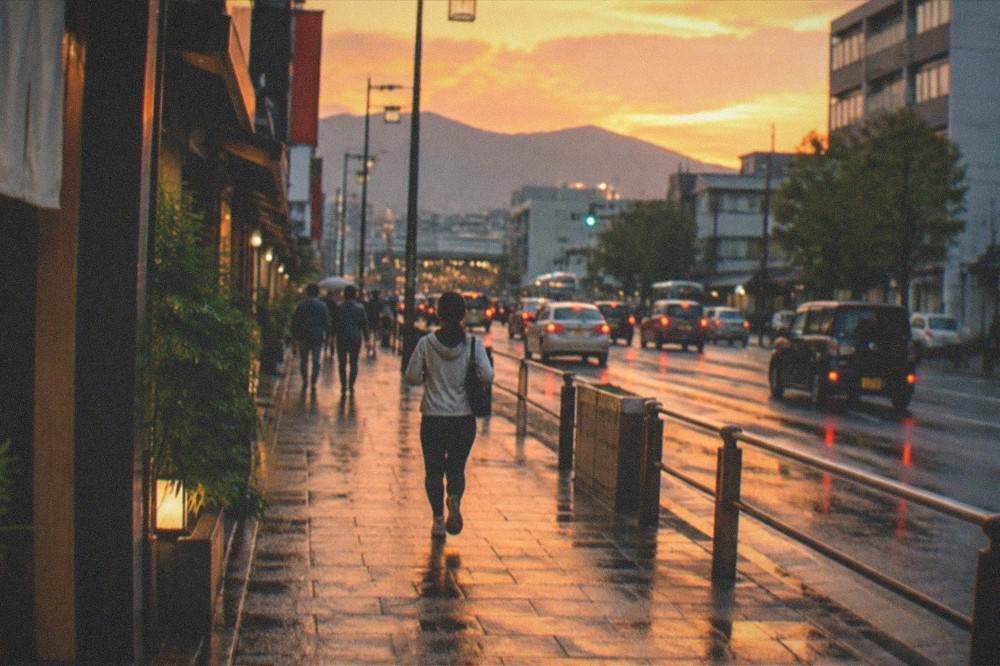 The Kyoto cityscape at dusk with the mountains silhouetted against an orange sky