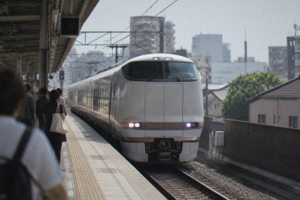 A limited express train pulling into Kyoto Station under a blue sky