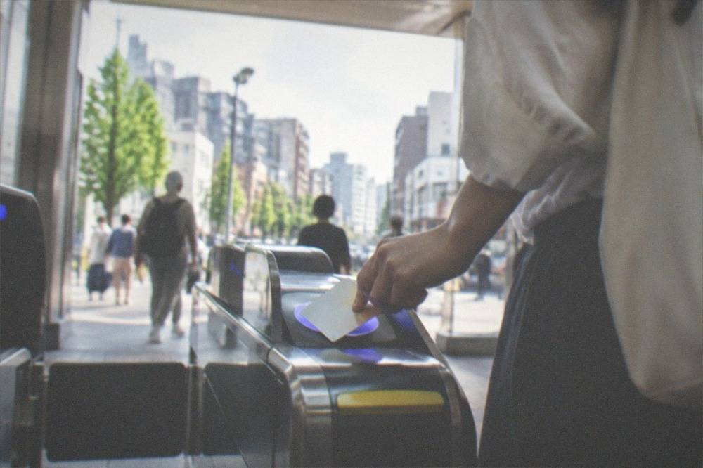 A traveller tapping an IC card on a station ticket gate in Japan