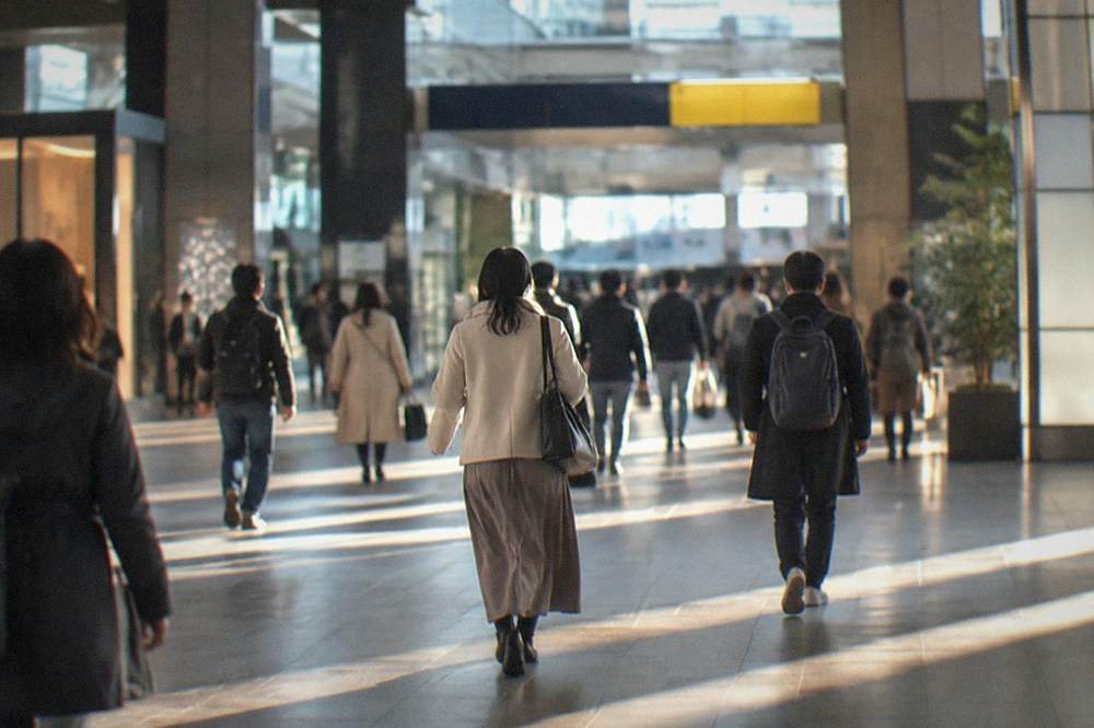 Passengers walking through a bright modern railway station concourse with departure boards overhead