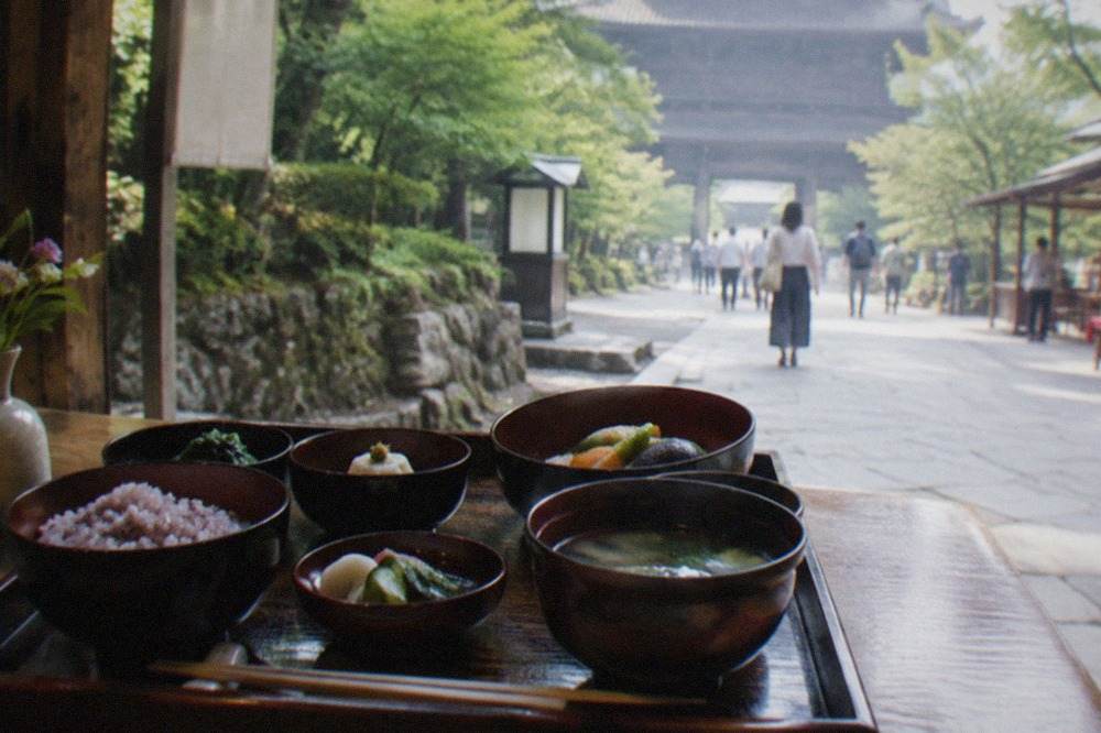 A multi-course vegetarian Japanese meal served in dark lacquer bowls on a wooden tray