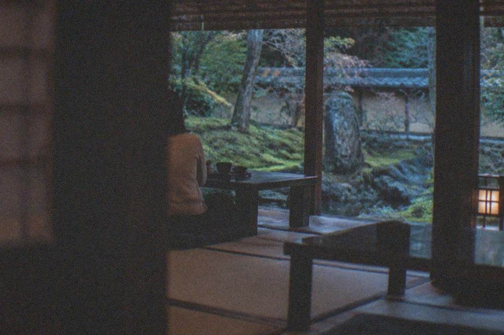 A quiet temple restaurant room with tatami flooring, low tables and a view of a moss garden
