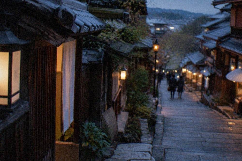 Stone steps of a preserved sloping street lined with traditional wooden shopfronts