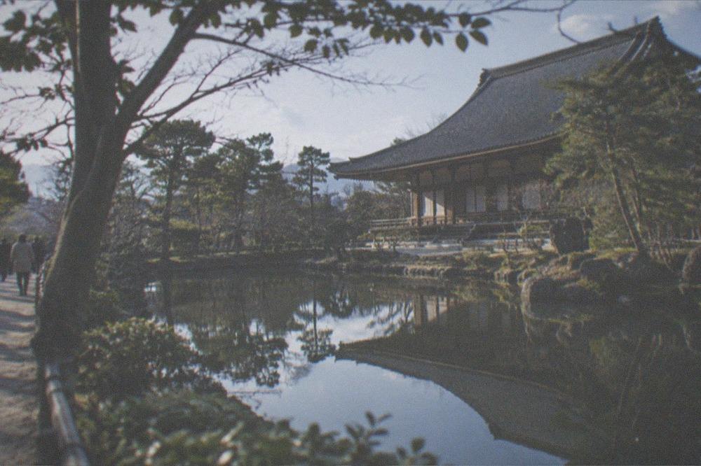 A temple hall reflected in a still pond surrounded by trees