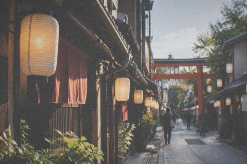 A shrine gate and rows of hanging lanterns lit against the evening sky