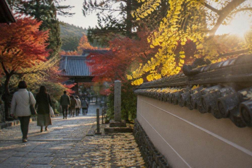 A stone path covered with fallen ginkgo leaves beside a temple wall