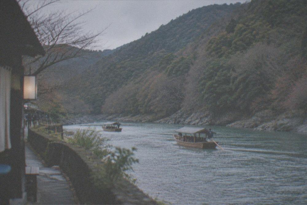 The wooden boats of the Hozugawa Kudari drifting along the river gorge below Arashiyama