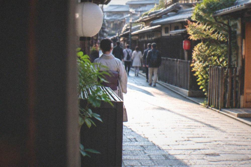 A quiet stone-paved alley in Gion at dusk with traditional wooden facades