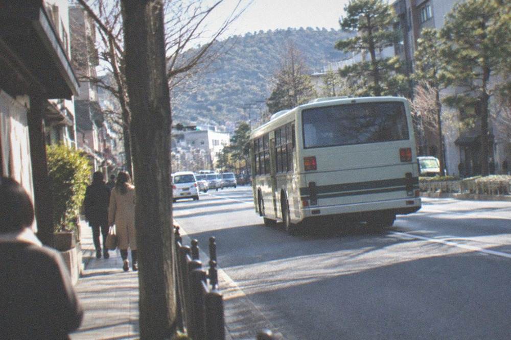 A city bus pulling away from a stop on a cold clear street in central Kyoto