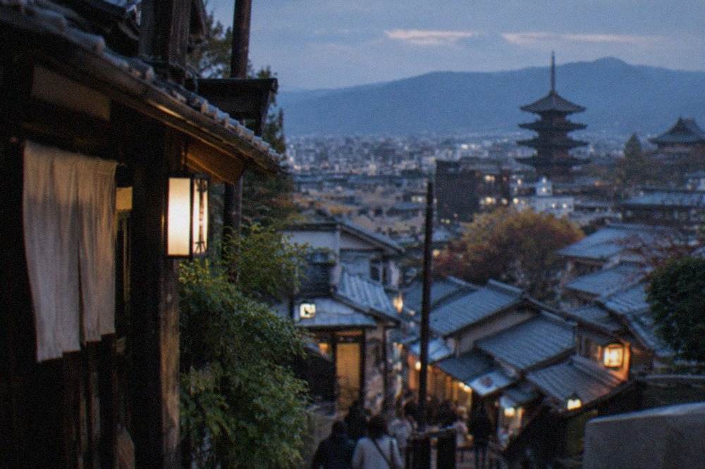 Kyoto rooftops and temple pagodas seen from a hillside at late afternoon