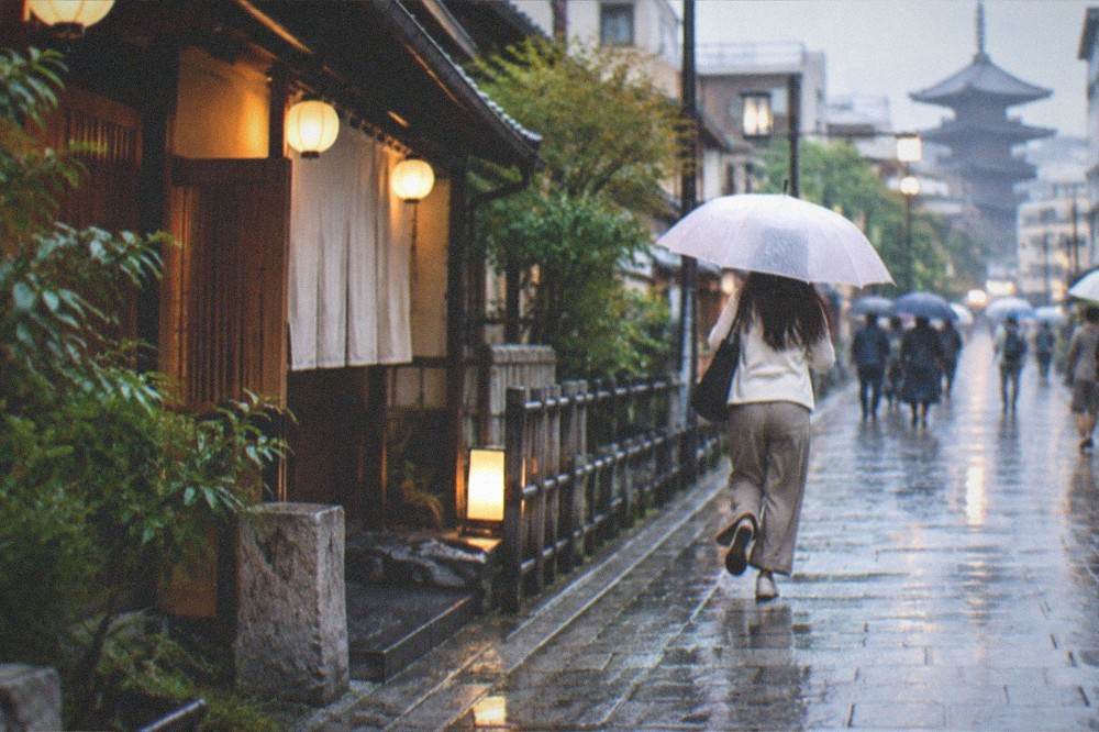 Rain falling on a stone street in Kyoto with umbrellas and lanterns