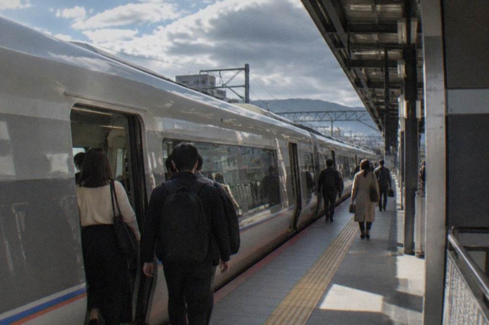 A limited express train standing at a platform in a Japanese railway station with passengers boarding