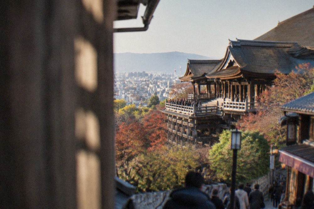 The long veranda of Kiyomizu-dera seen from the slope below, with the city spreading out behind the temple