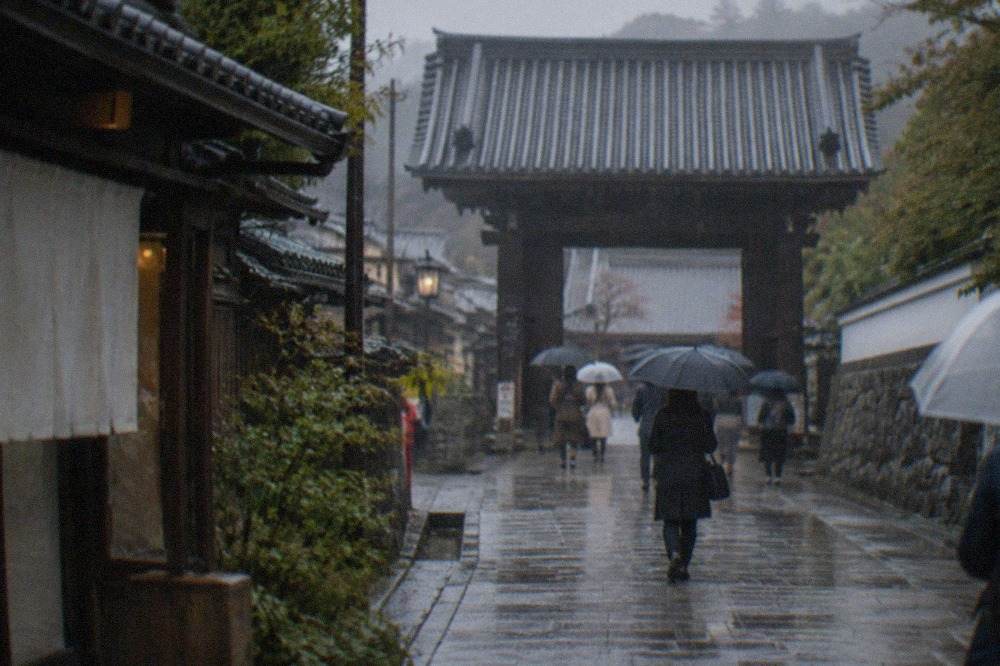 Wet stone path leading to a temple gate in Kyoto during soft rain