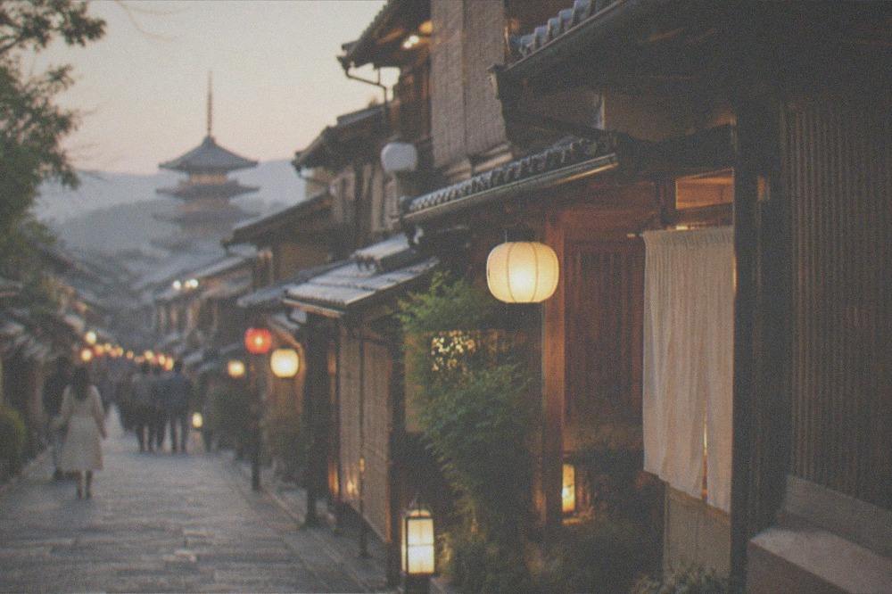 Traditional wooden machiya teahouses along a lantern-lit street in Gion at dusk